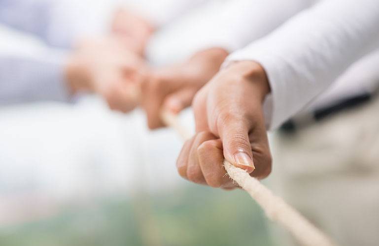 Mehrere Menschen ziehen gemeinsam mit vereinten Kräften an einem Tau